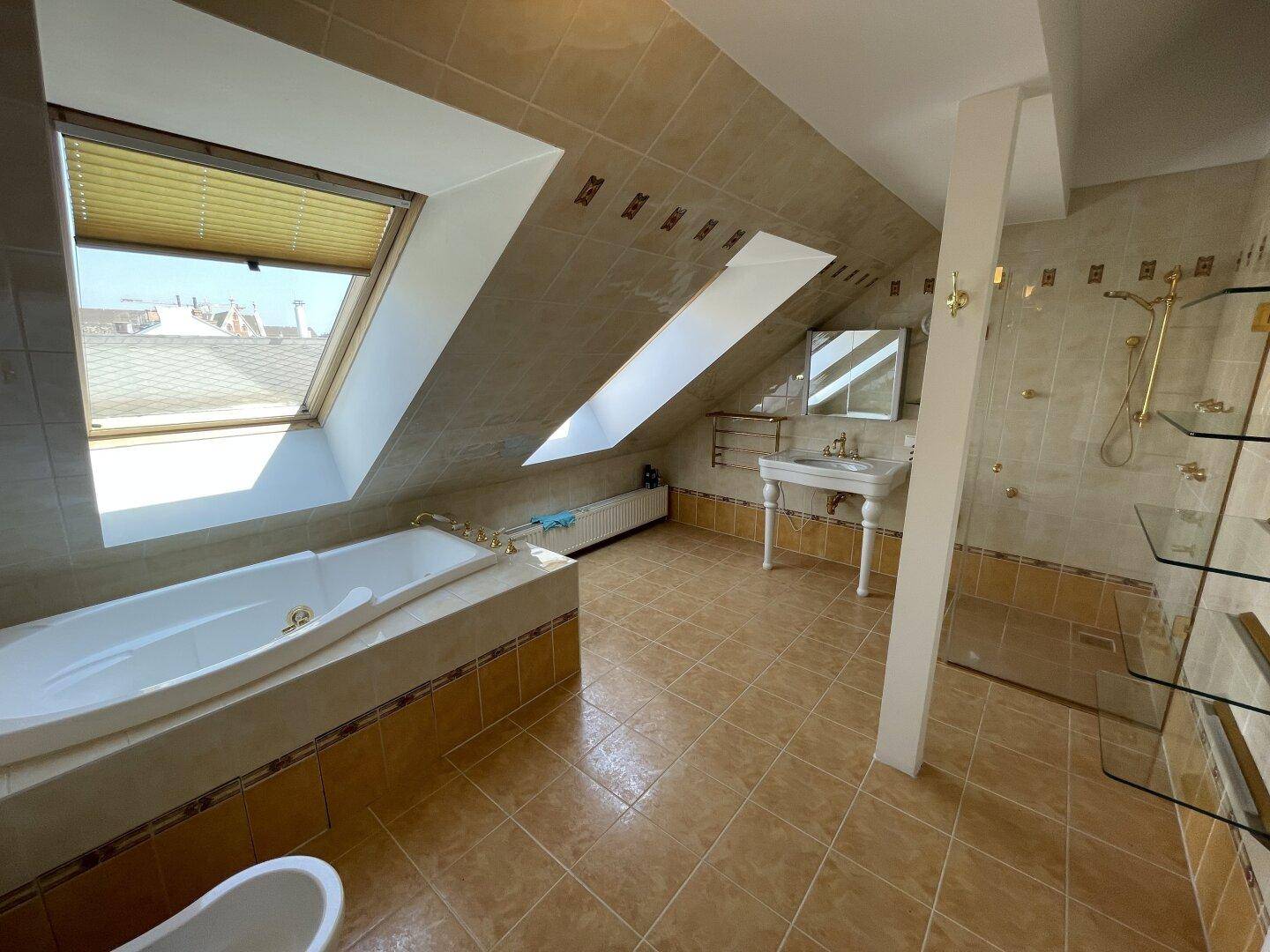 Geräumiges Badezimmer mit Badewanne, Dusche, Waschtisch und Dachfenstern.