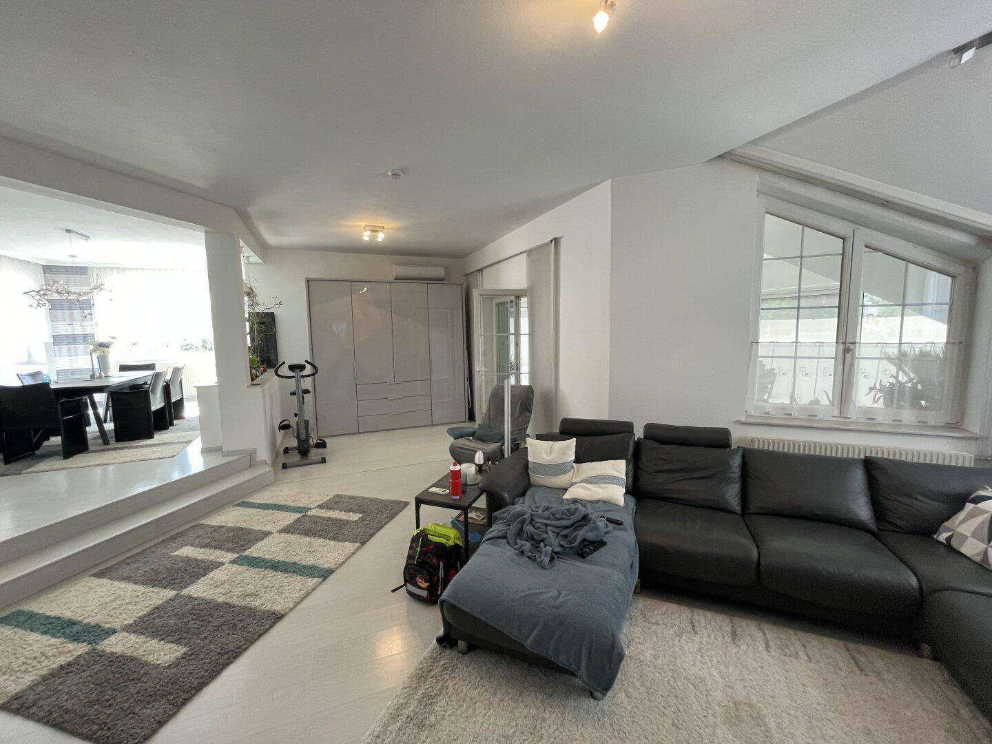 Heller Wohnbereich mit bequemer Couch, Teppichen und Blick auf den erhöhten Essbereich.