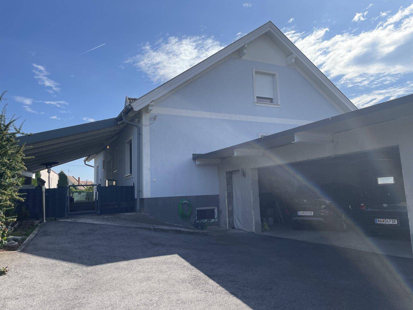 Seitenansicht des Hauses mit einem überdachten Carport und Zufahrt.