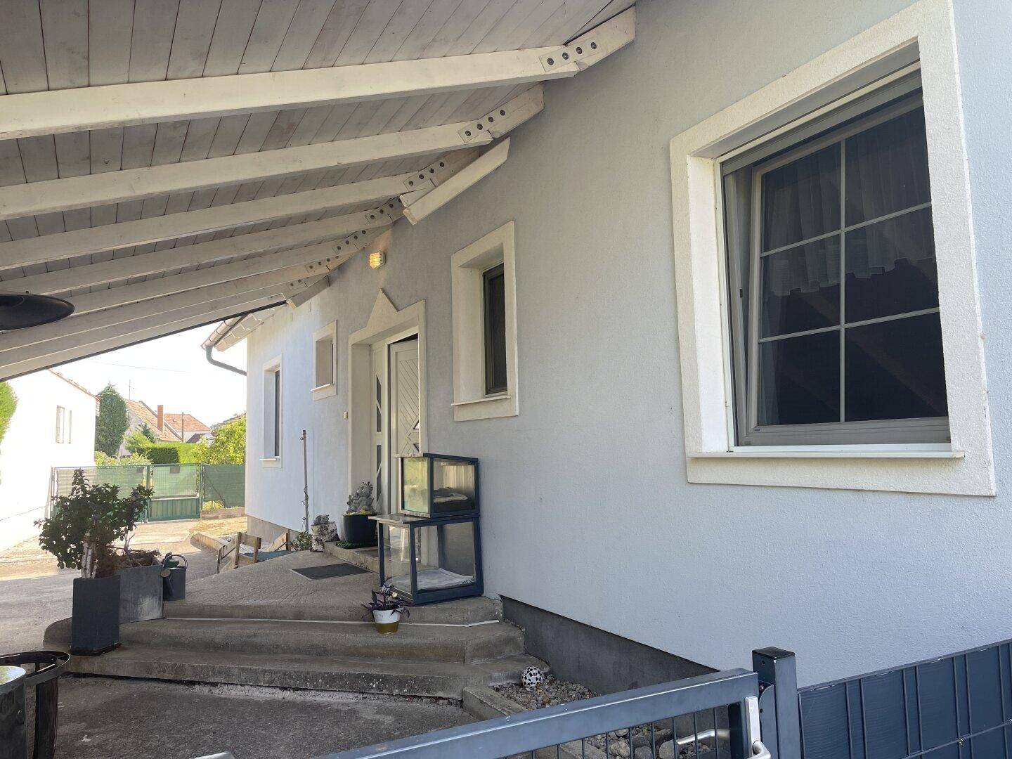 Überdachter Eingangsbereich des Hauses unter dem Carport mit Stufen.