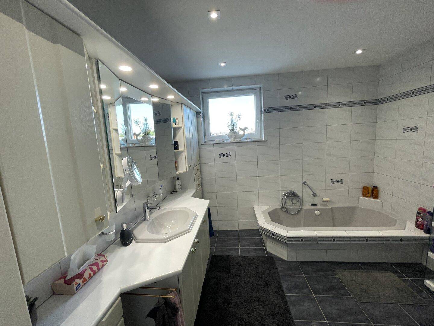 Geräumiges Badezimmer mit Eckbadewanne, Doppelwaschbecken und Fenster für Tageslicht.