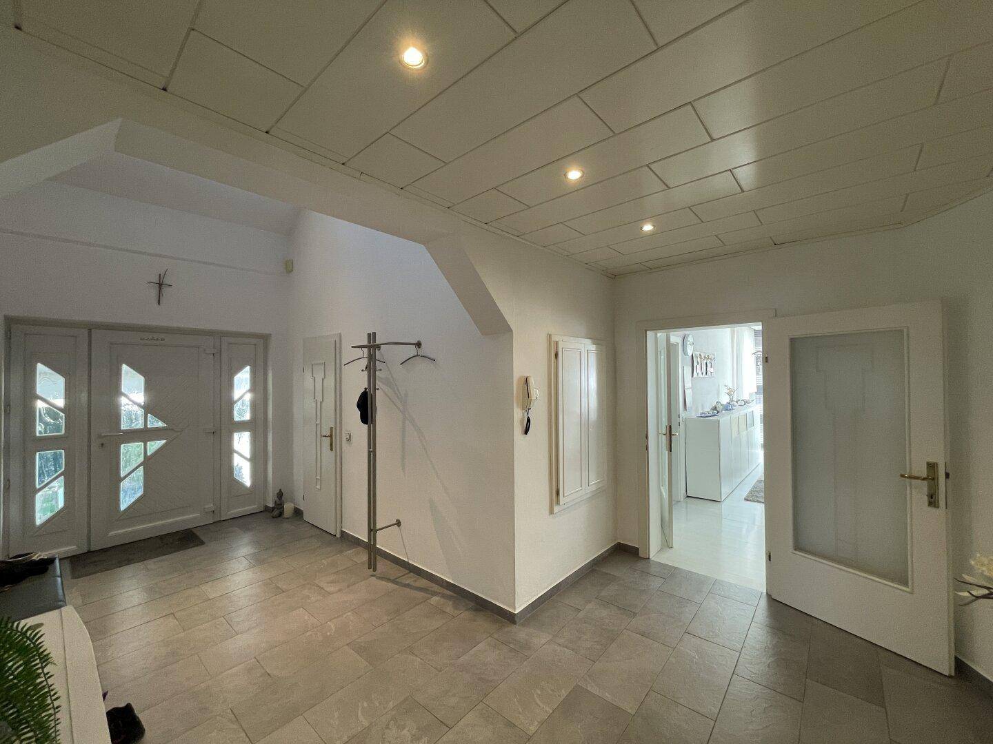 Geräumiger Eingangsbereich mit Fliesenboden, Garderobe und Zugang zu weiteren Räumen.