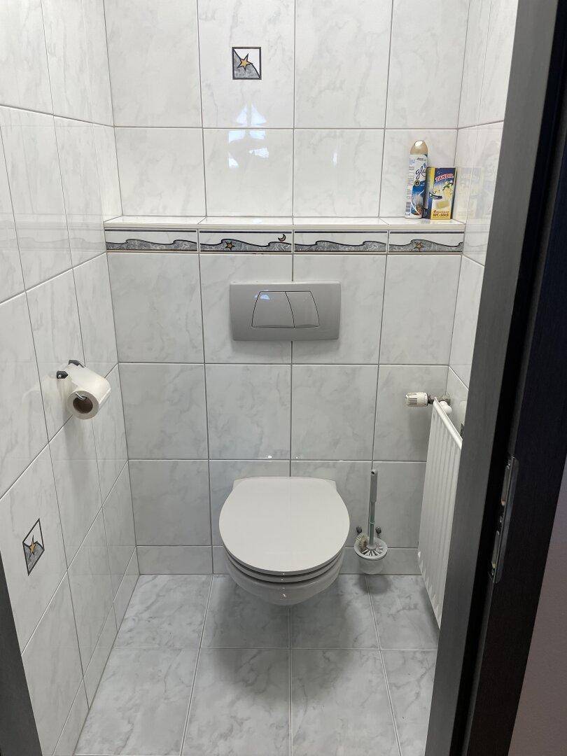 Kleines Gäste-WC mit weißen Fliesen und Wand-WC, praktisch und pflegeleicht.