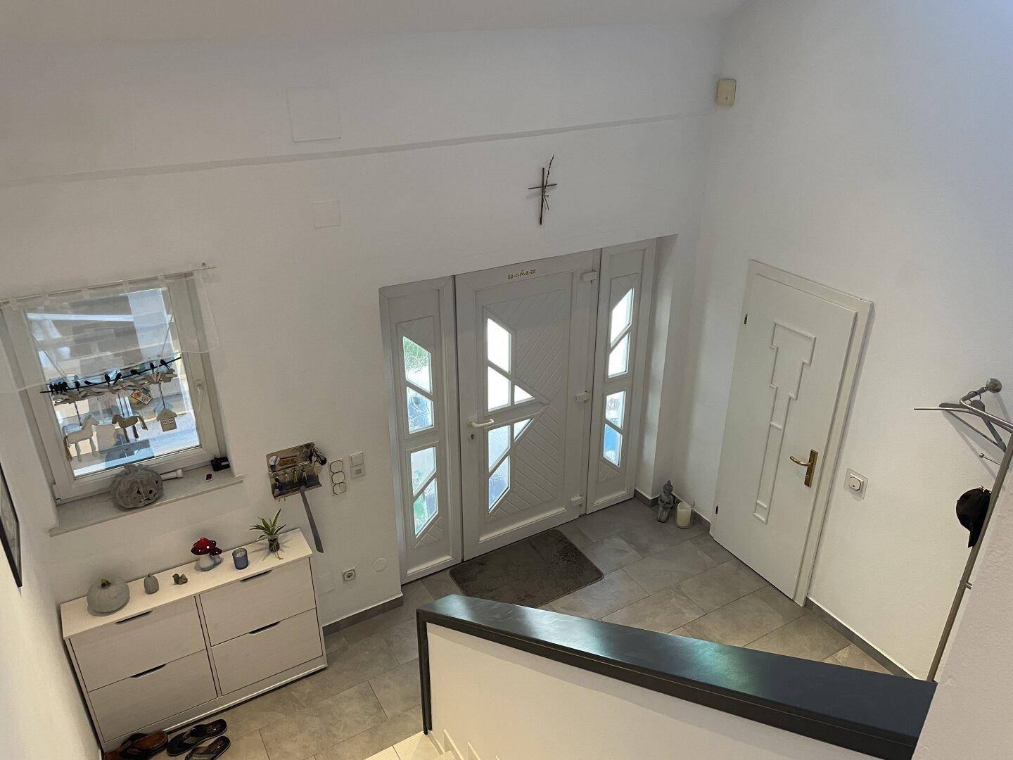 Heller Eingangsbereich mit doppelter Haustür, Fenster und Schuhschrank, einladend gestaltet.