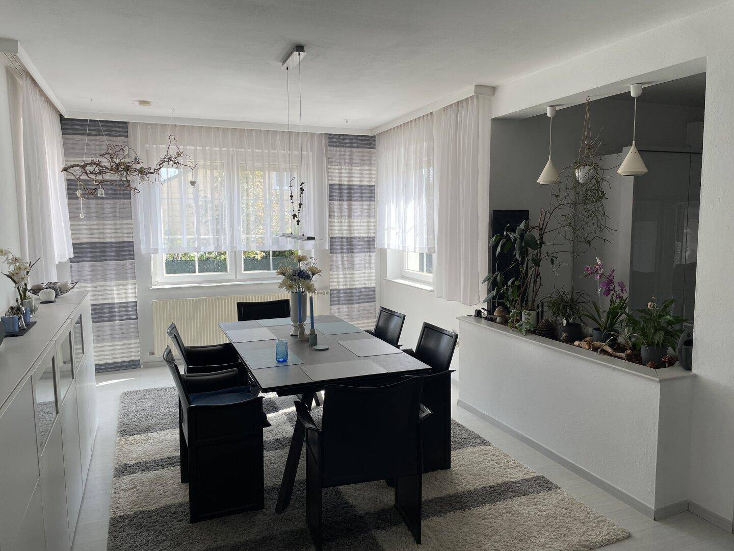 Heller Essbereich mit elegantem Esstisch, passenden Stühlen und Blick in den Wohnbereich.