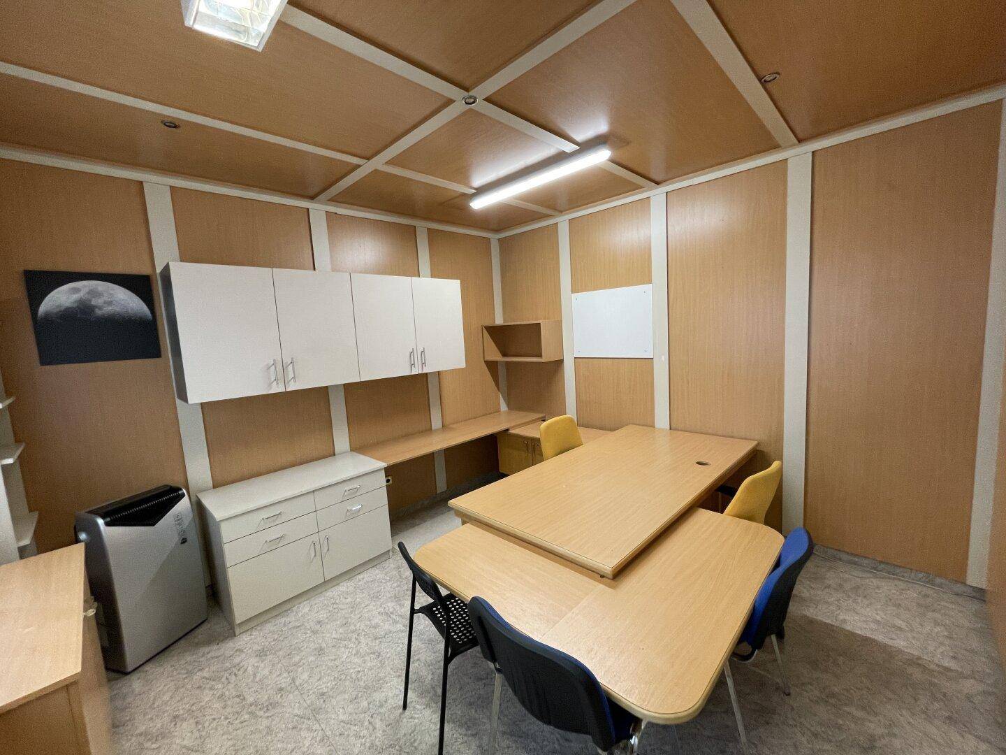 Geräumiges Büro mit mehreren Arbeitsplätzen, Holzvertäfelung und praktischen Aufbewahrungslösungen.