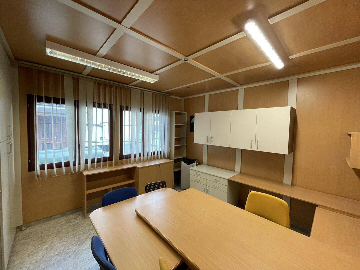Modern eingerichtetes Büro mit Holzvertäfelung, Schreibtischen und großen Fenstern für viel Licht.