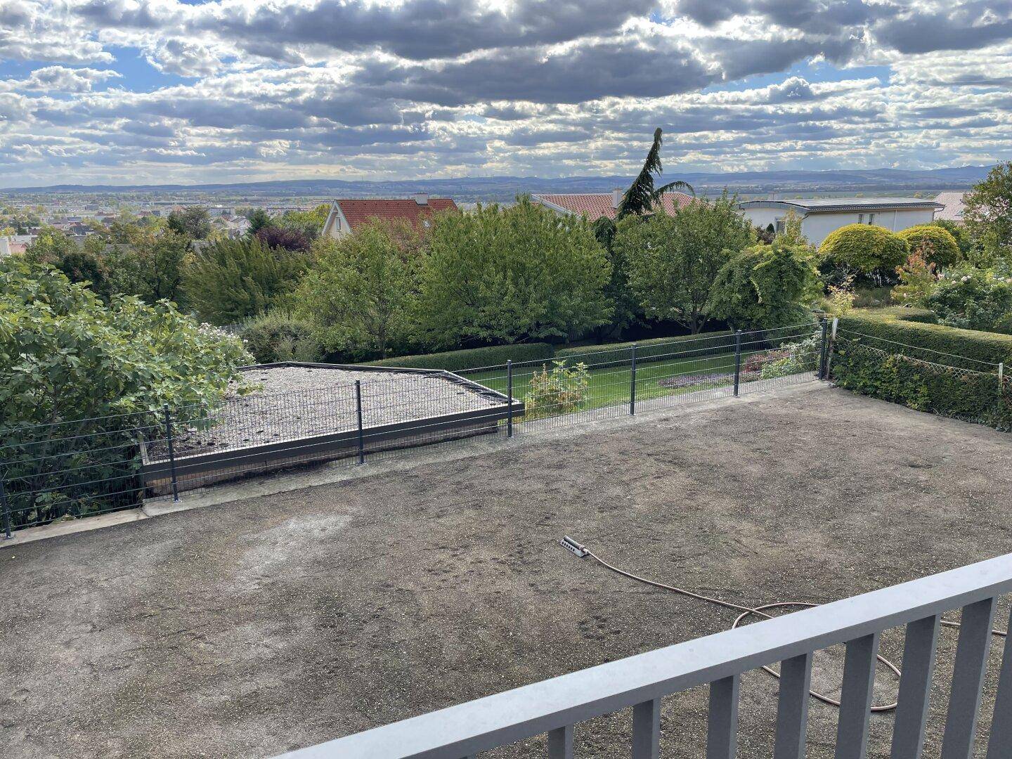 Blick von einem Balkon auf einen neu angelegten Gartenbereich und die weite, grüne Landschaft.