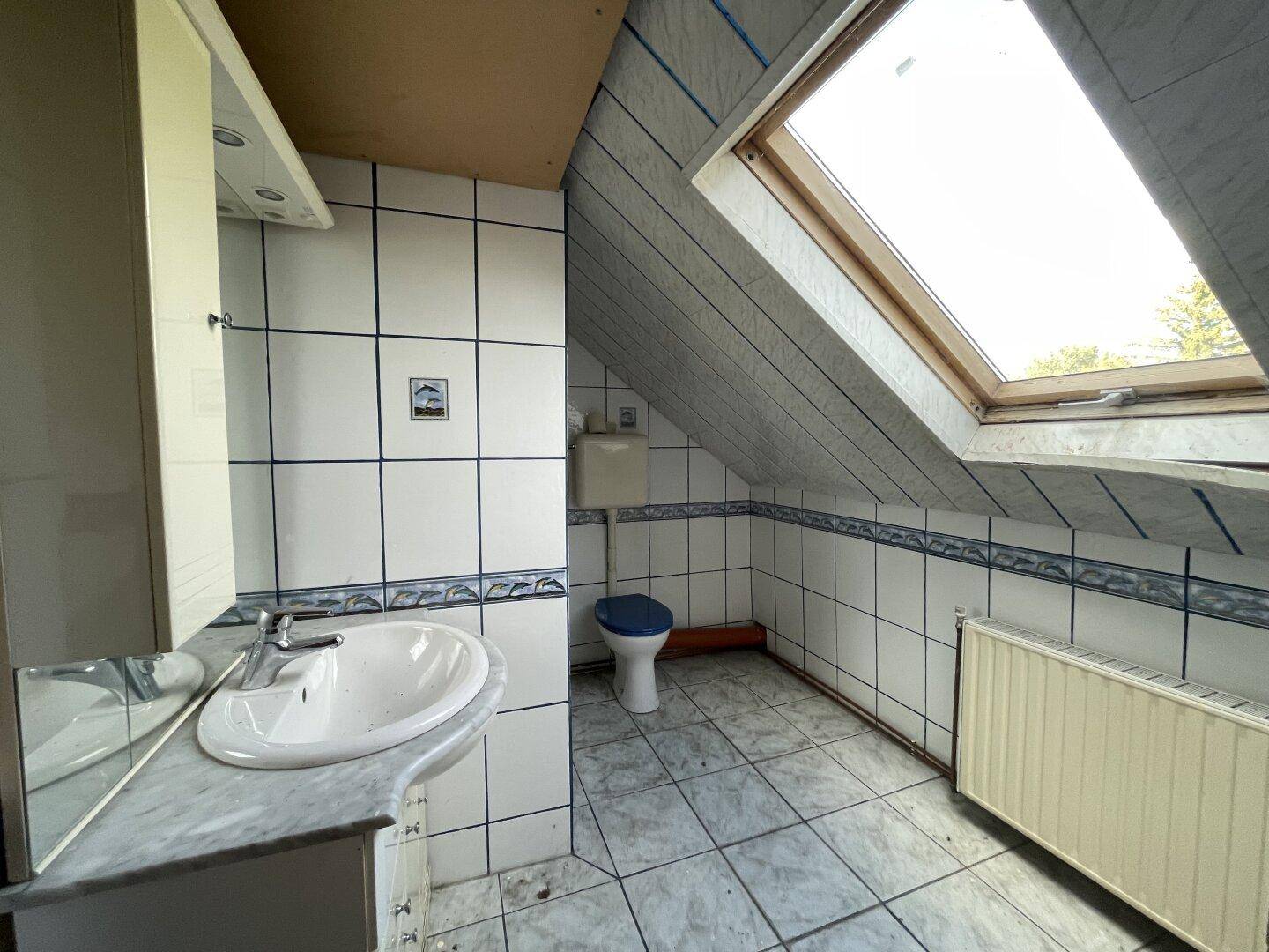 Badezimmer im Dachgeschoss mit Fliesen, Dachfenster und schräger Decke.