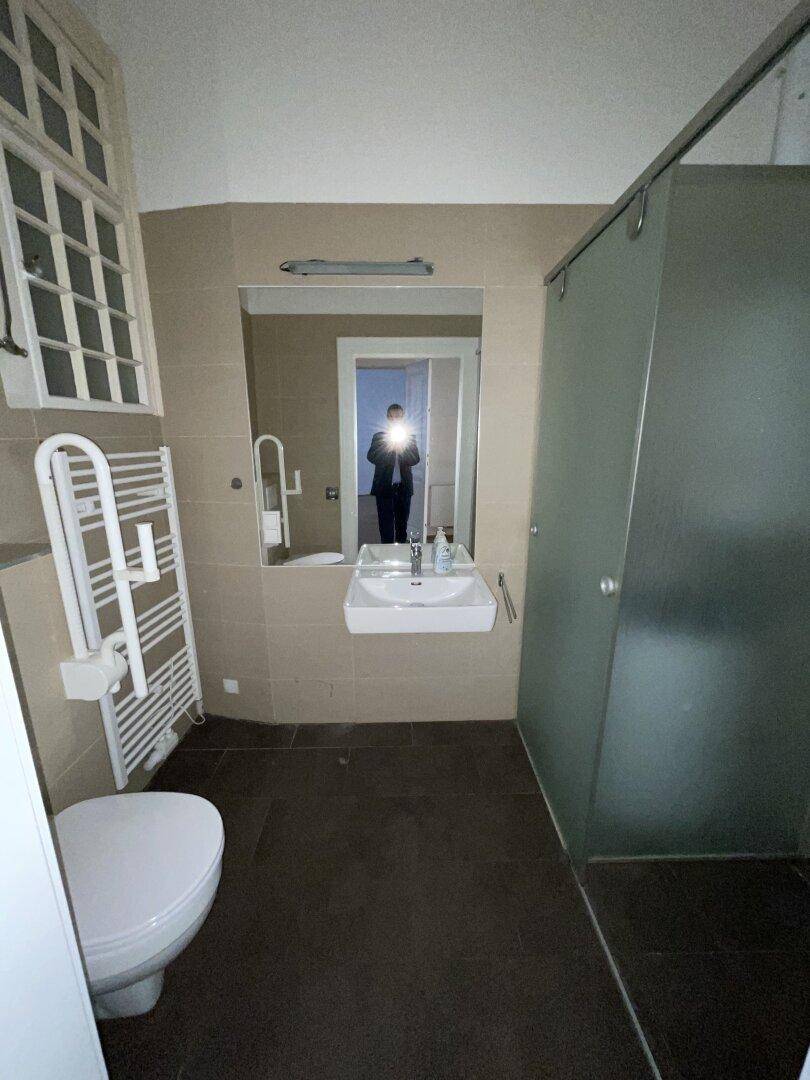 Modernes Badezimmer mit Dusche, beheiztem Handtuchhalter und Fenster.