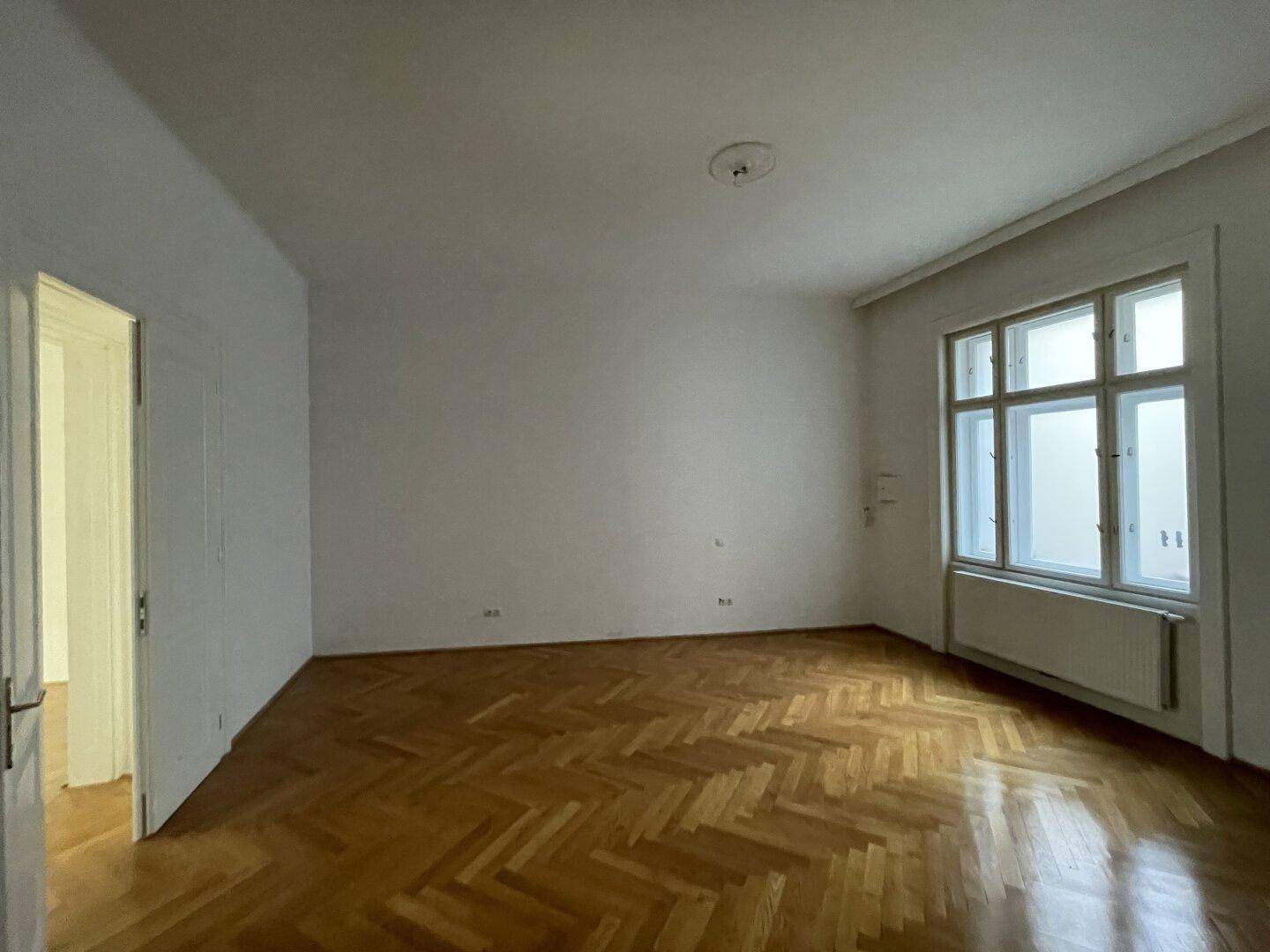 Heller Raum mit Fischgrätparkett und großen Fenstern, bereit zur individuellen Gestaltung.