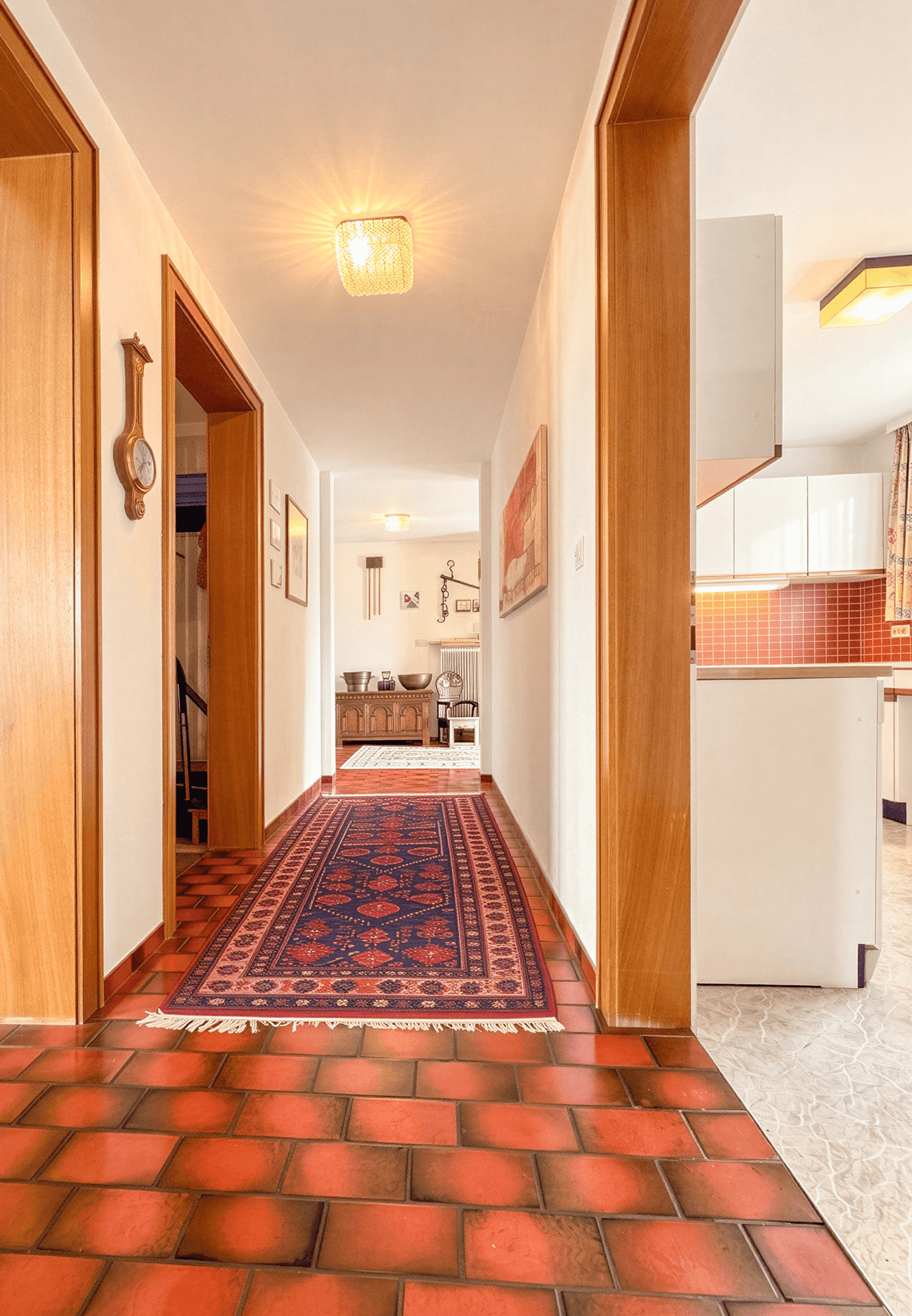 Langer Flur mit Terrakotta-Fliesenboden, der zu den verschiedenen Räumen des Hauses führt.