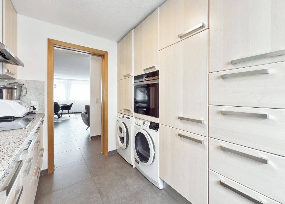 Helle Küche mit integrierten Geräten und Zugang zum Wohnbereich.