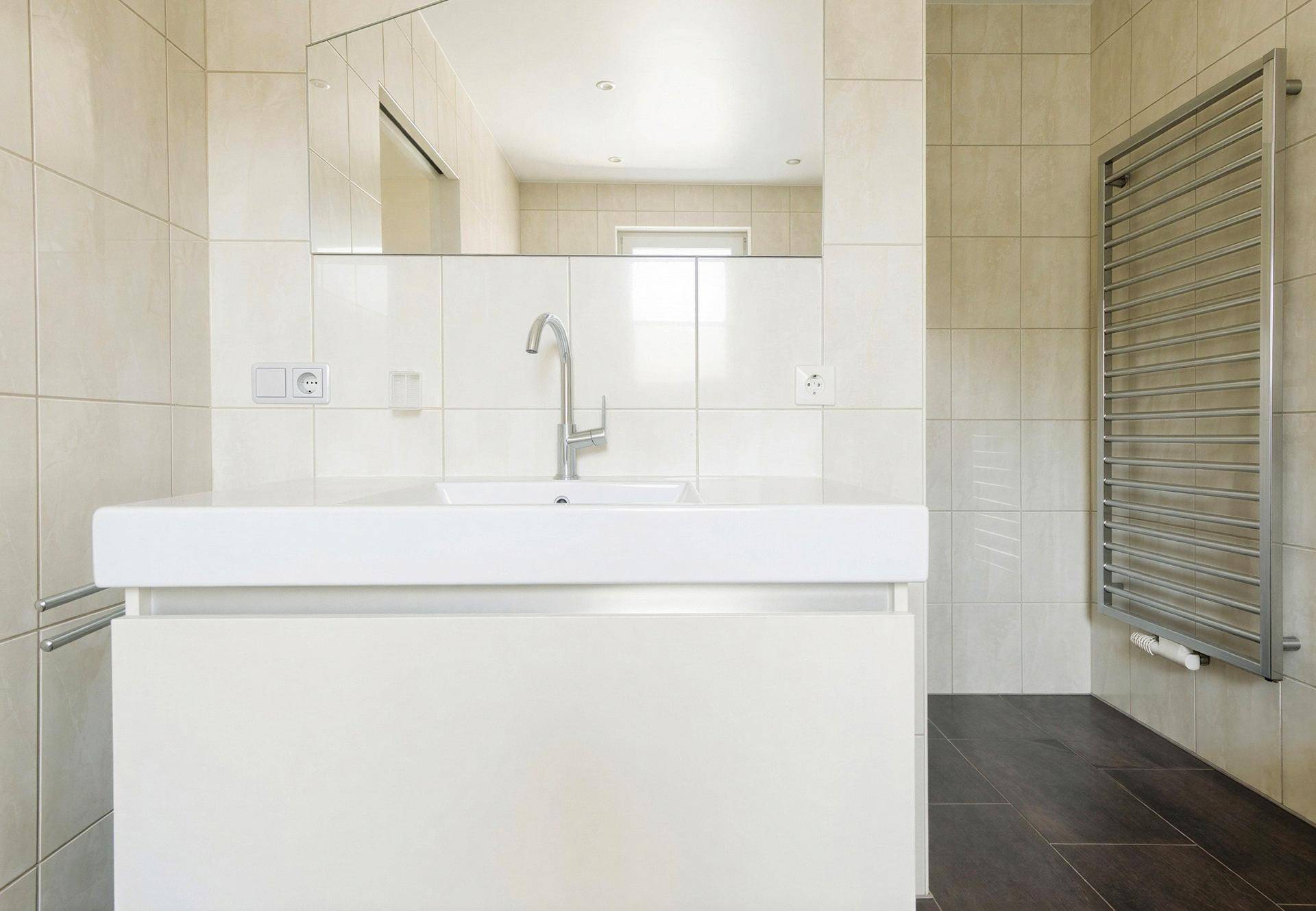 Modernes Badezimmer mit Waschtisch, großem Spiegel und beheiztem Handtuchhalter.