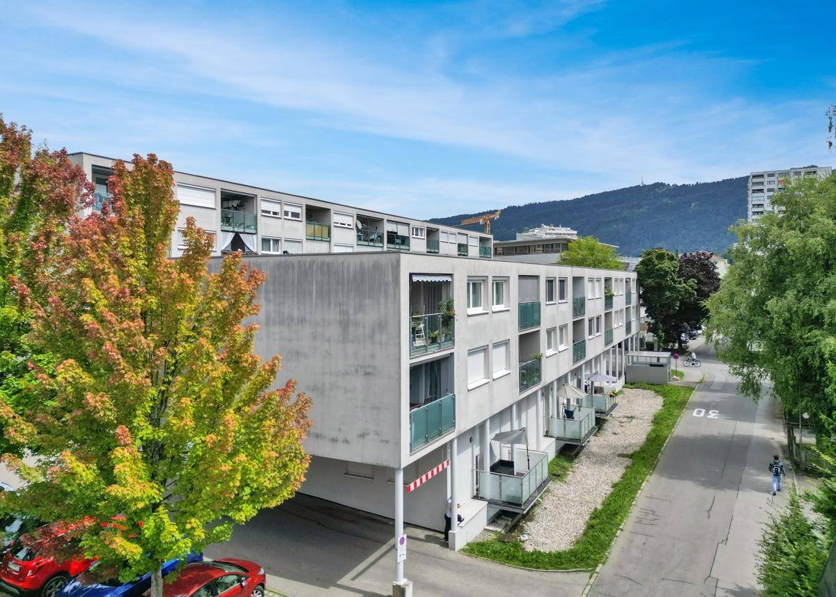 Moderne Wohnanlage mit mehreren Balkonen und Bäumen in der Umgebung.