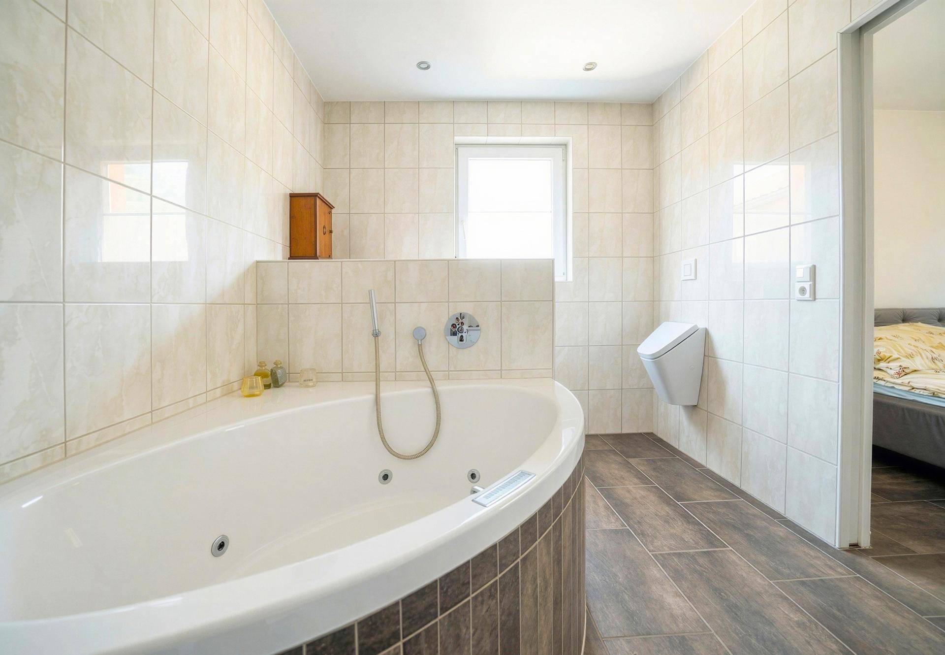 Geräumiges Badezimmer mit Eckbadewanne, Fliesenwänden und separatem Urinal.