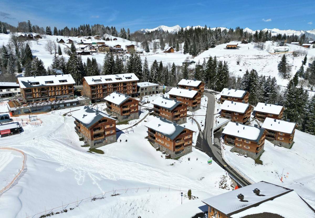 Weitläufige Ferienanlage mit mehreren Chalets in verschneiter Berglandschaft, umgeben von Wäldern.
