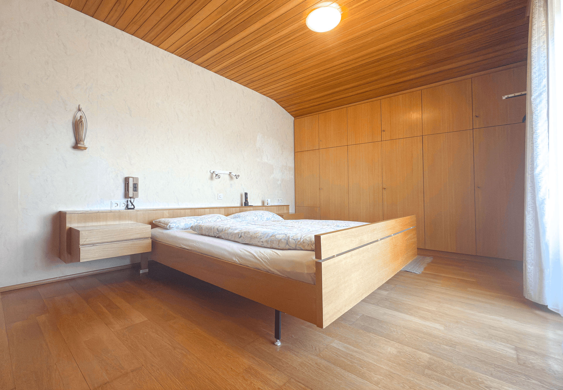 Schlafzimmer mit Holzdecke, Parkettboden und Einbauschränken für viel Stauraum.