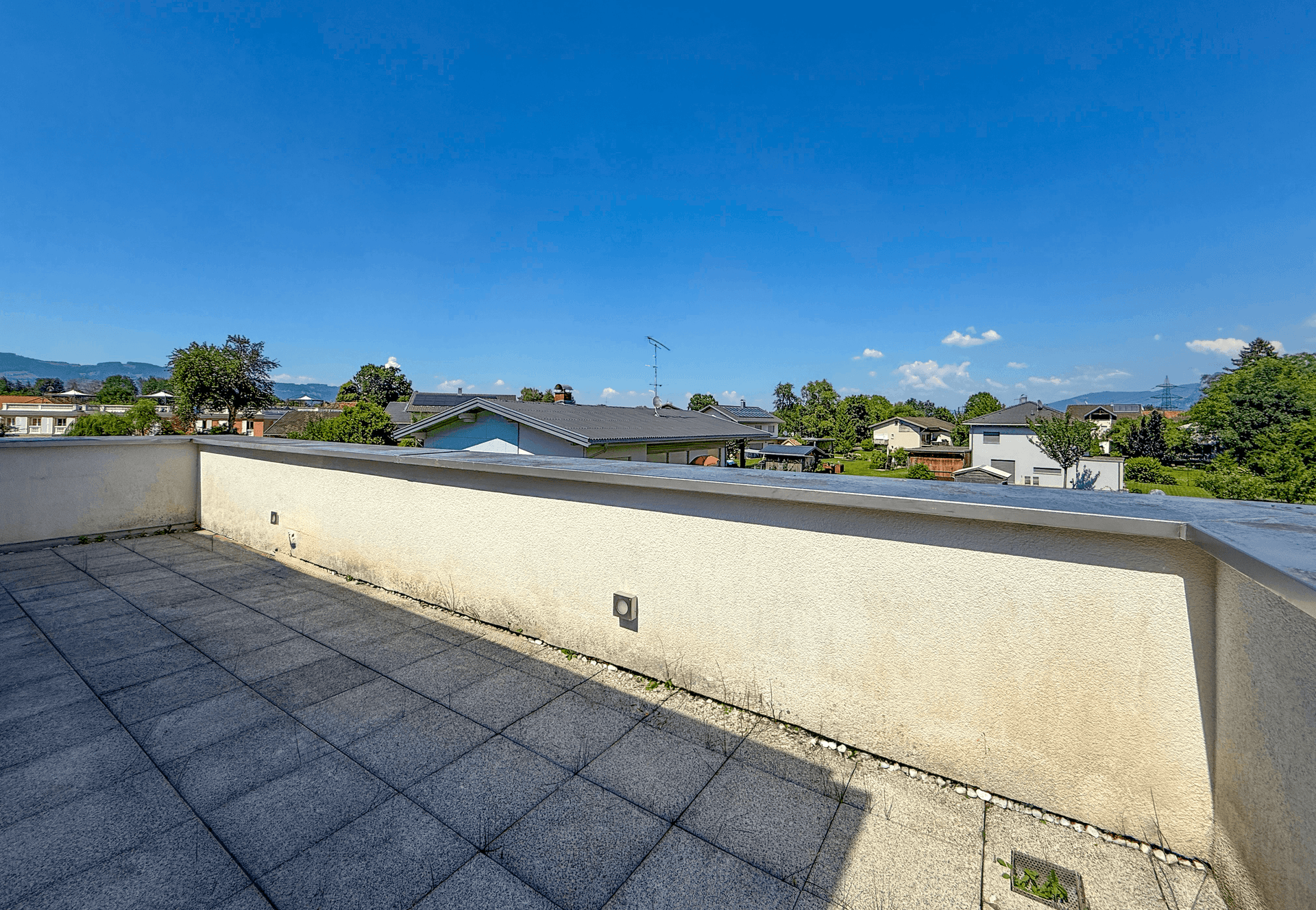Weitläufige Dachterrasse mit Fliesenboden und Panoramablick über die Landschaft.