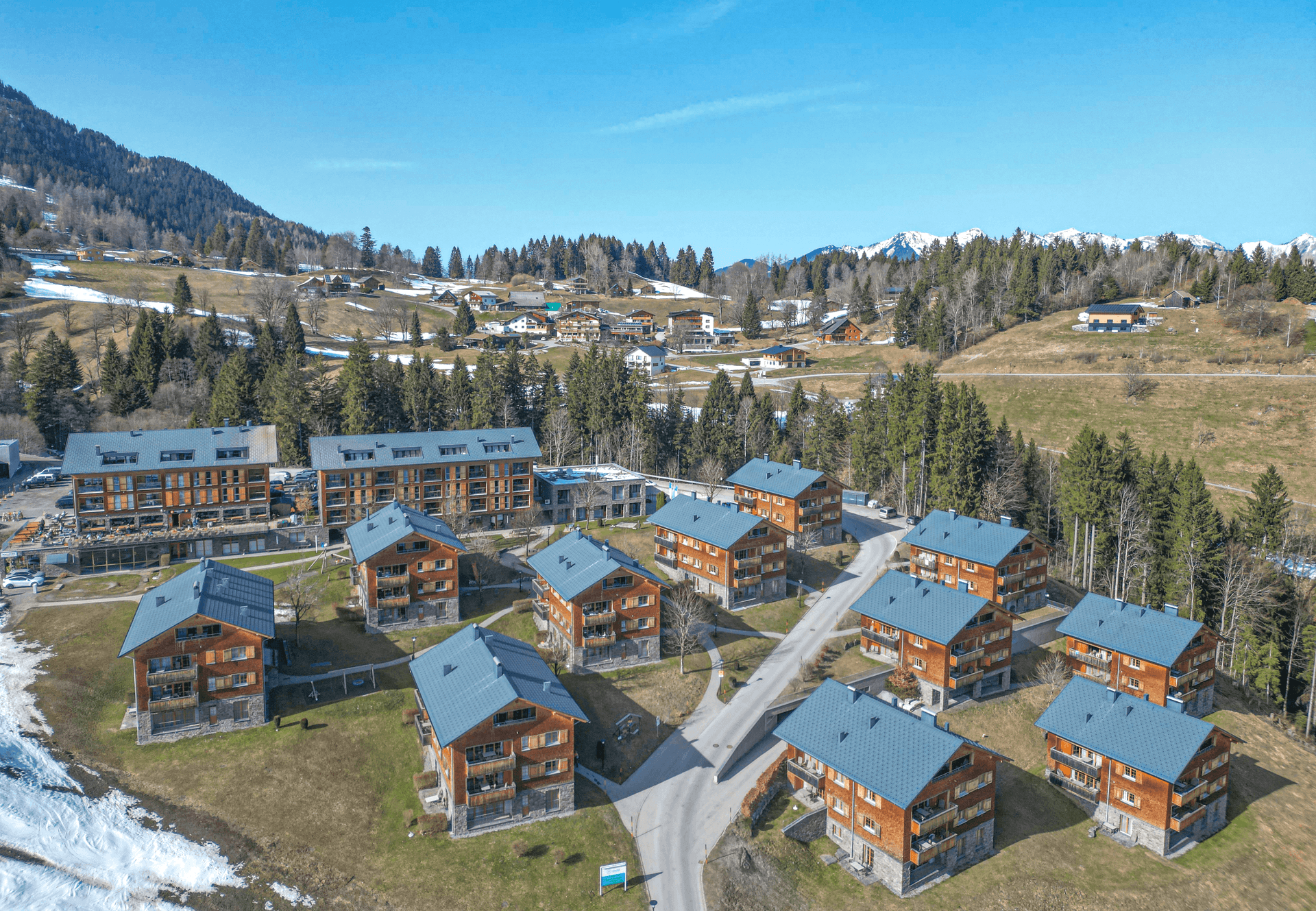 Panoramablick aus der Luft auf eine moderne Wohnsiedlung eingebettet in eine Berglandschaft.