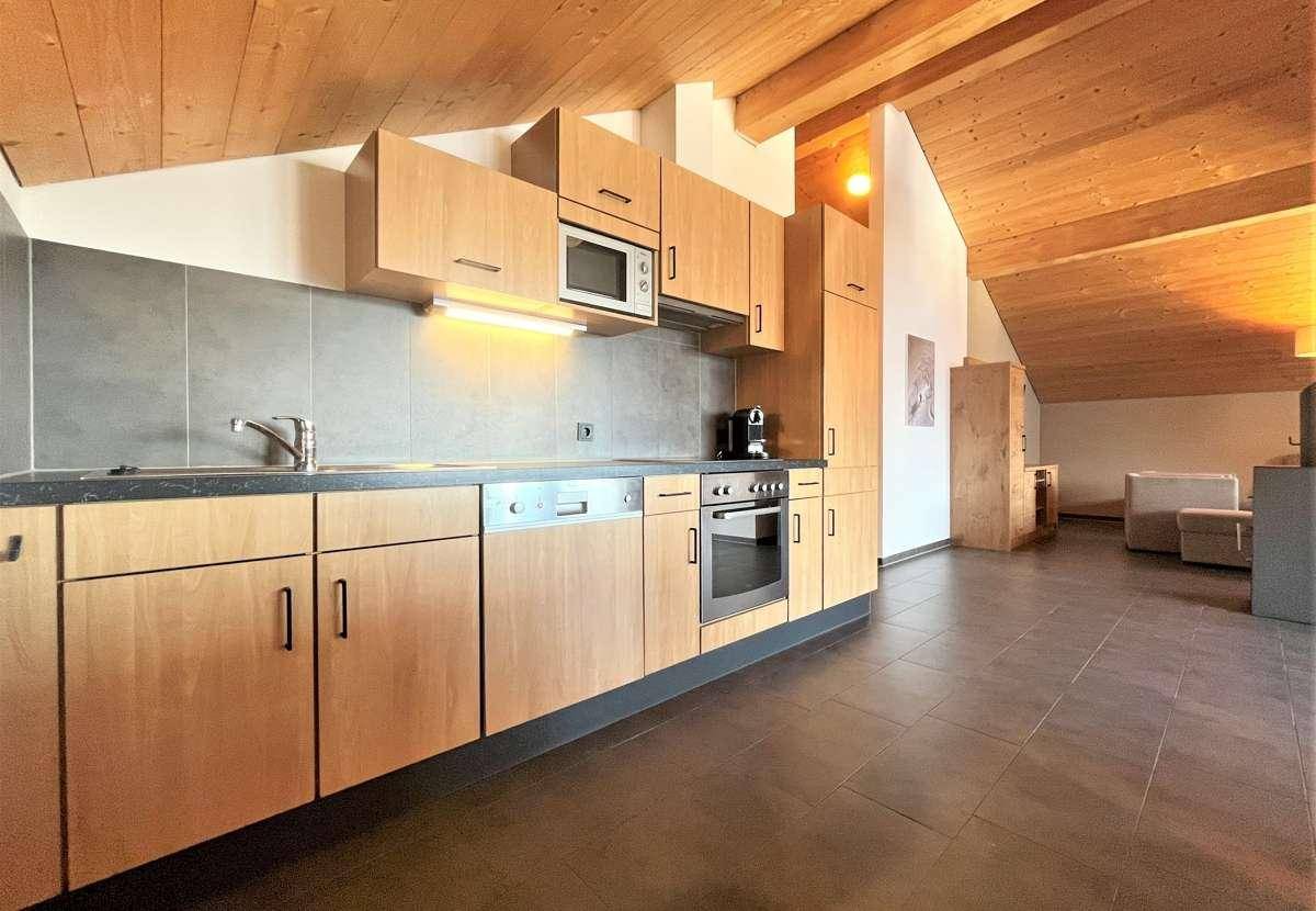 Moderne Holzküche mit integrierten Geräten, dunkler Arbeitsplatte und Fliesenrückwand.