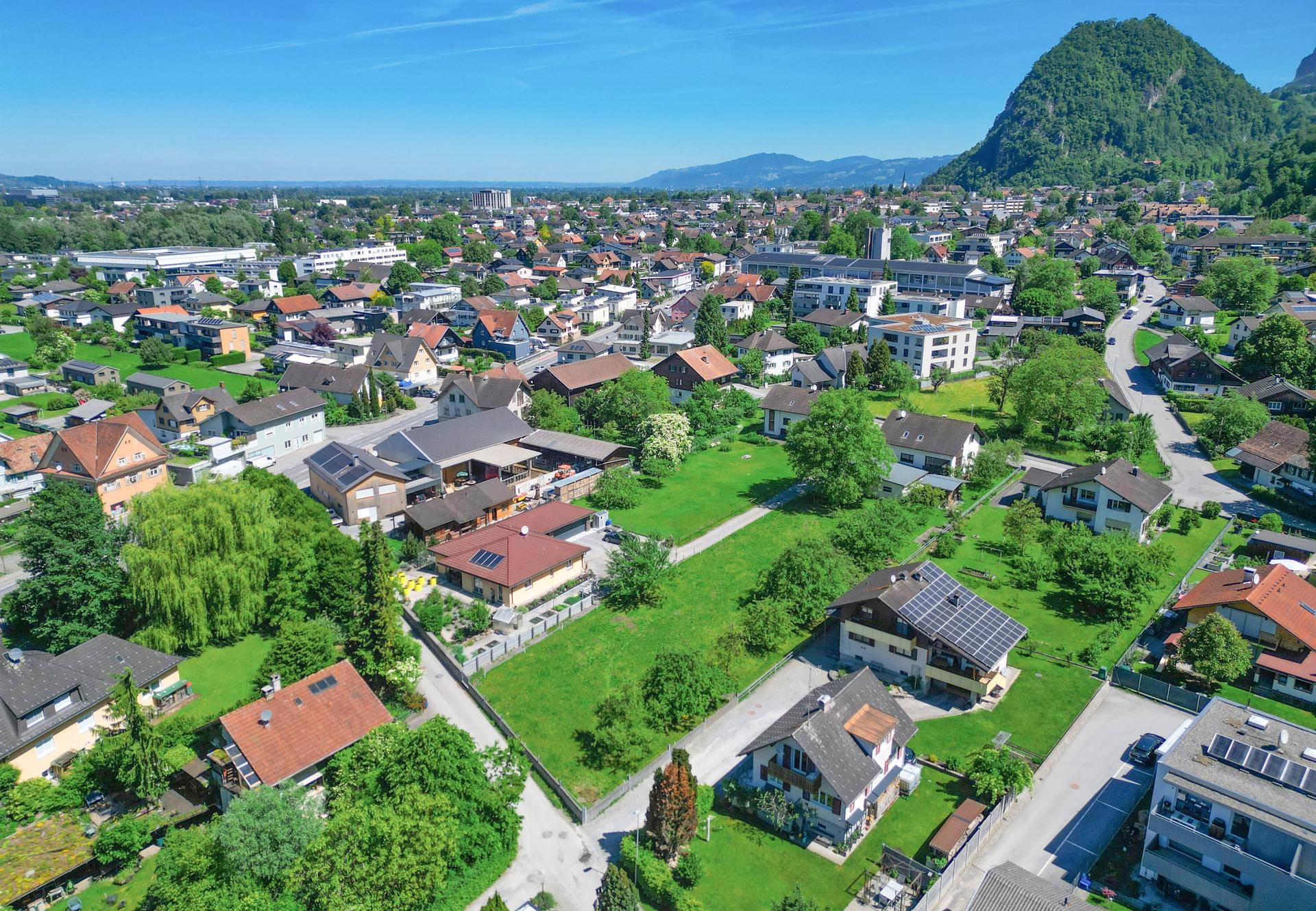 Panoramablick aus der Luft auf die Wohnsiedlung mit Bergen im Hintergrund.