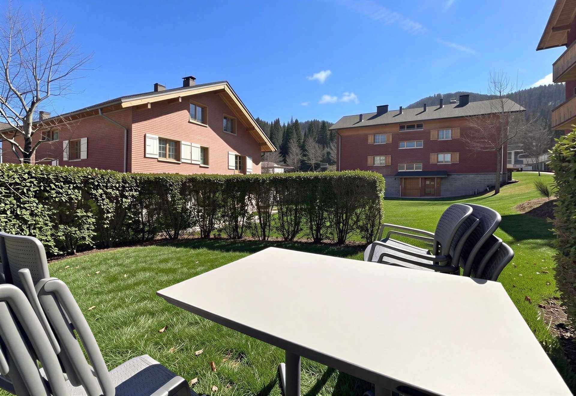 Gemütlicher Gartenbereich mit Tisch und Stühlen, umgeben von grünen Hecken.