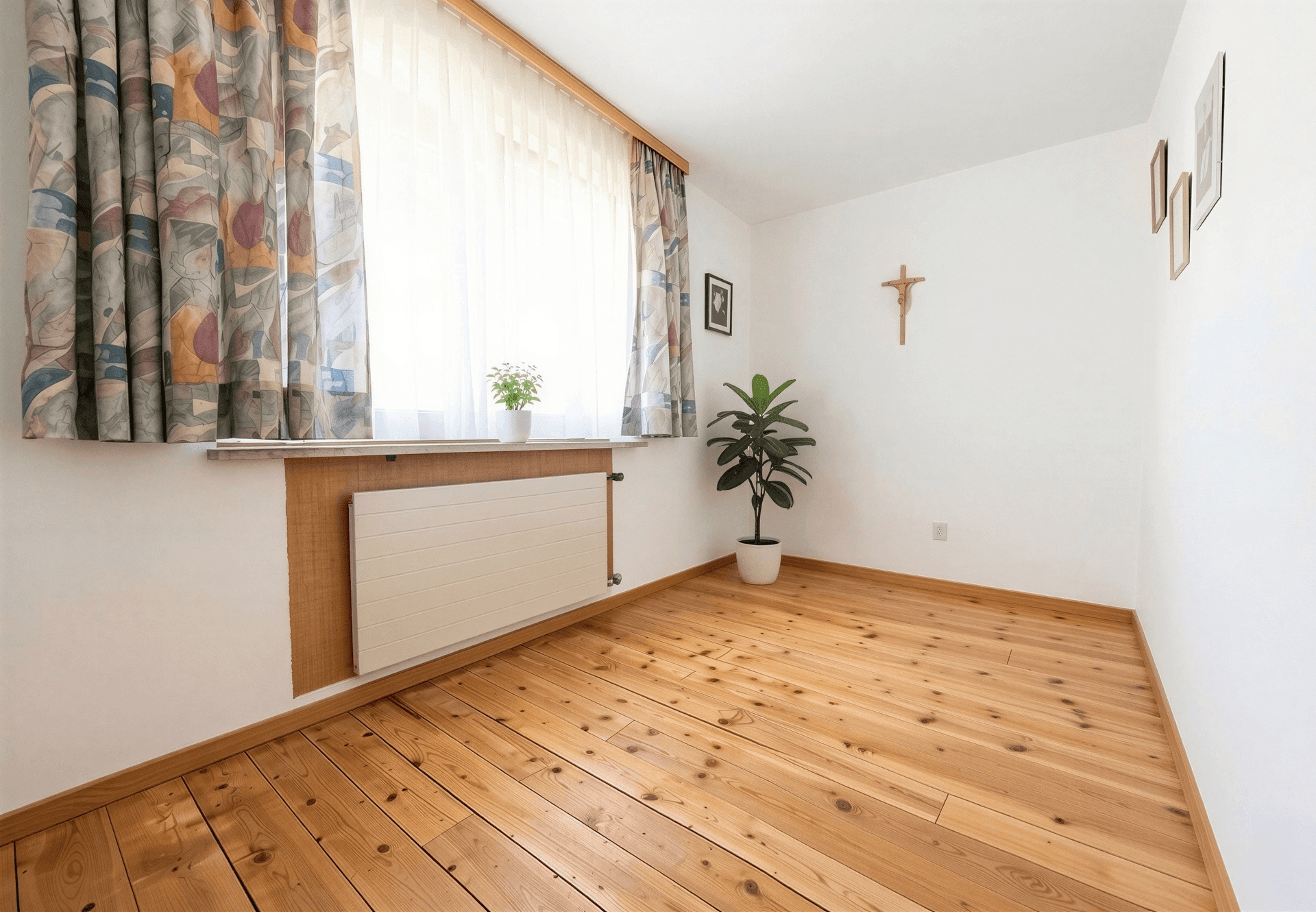 Kleiner Raum mit Holzdielenboden und Fenster, ideal als Arbeits- oder Gästezimmer.