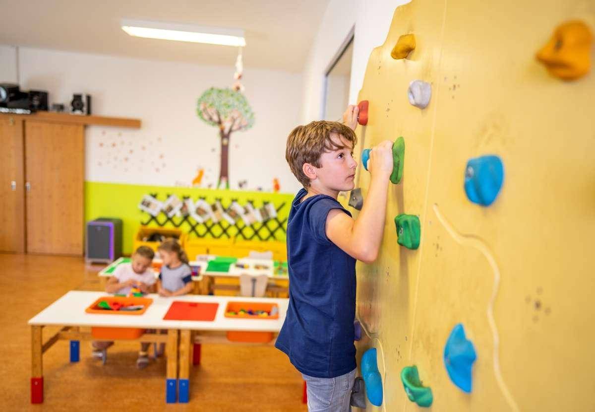 Bunter Spielbereich für Kinder mit Kletterwand und Tischen.