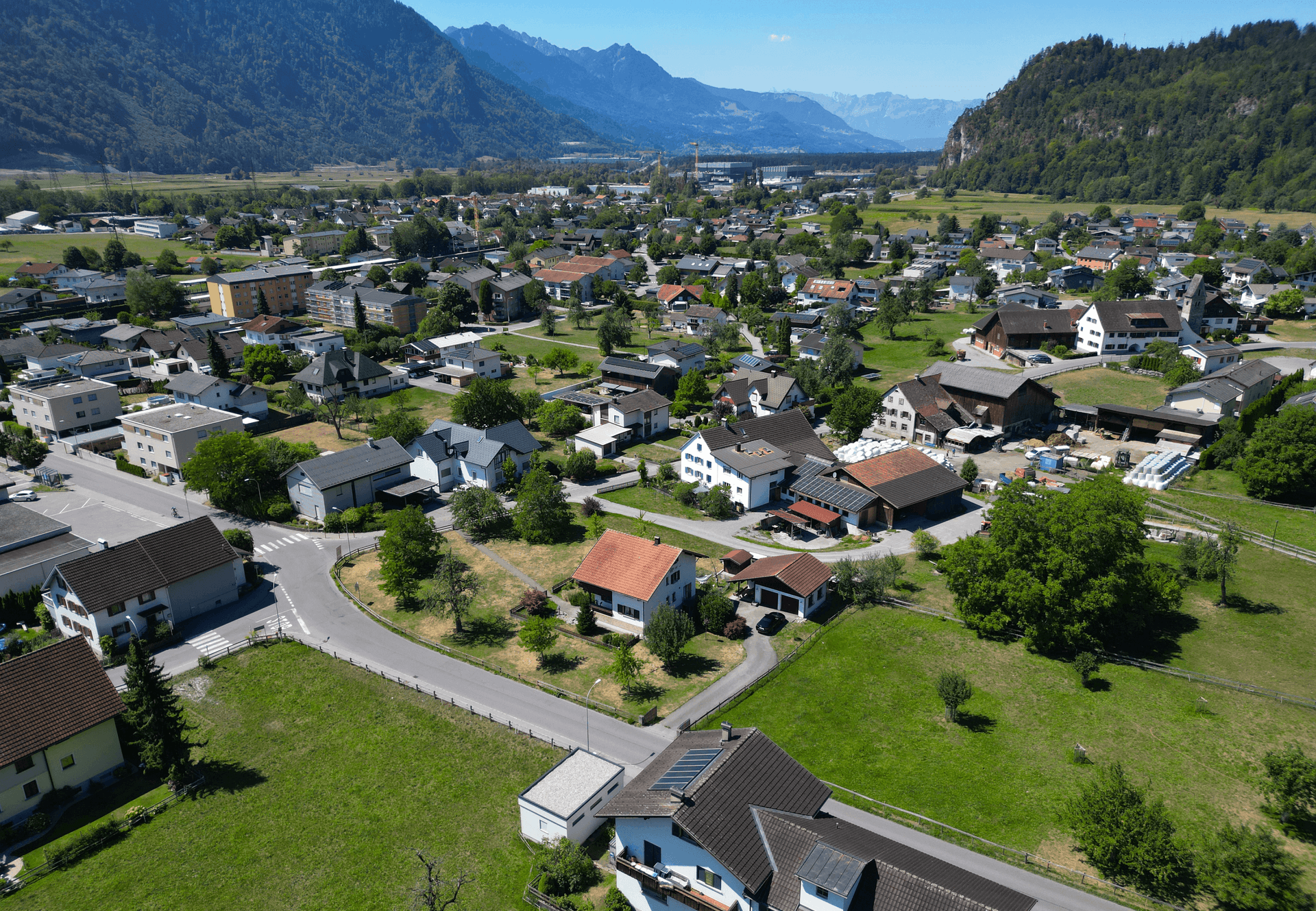 Weitläufige Luftaufnahme der Siedlung mit Häusern, Straßen und grünen Flächen.
