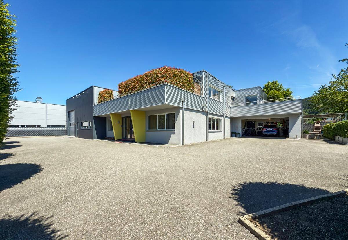 Moderne Gewerbeimmobilie mit großem Parkplatz und begrünten Terrassen.