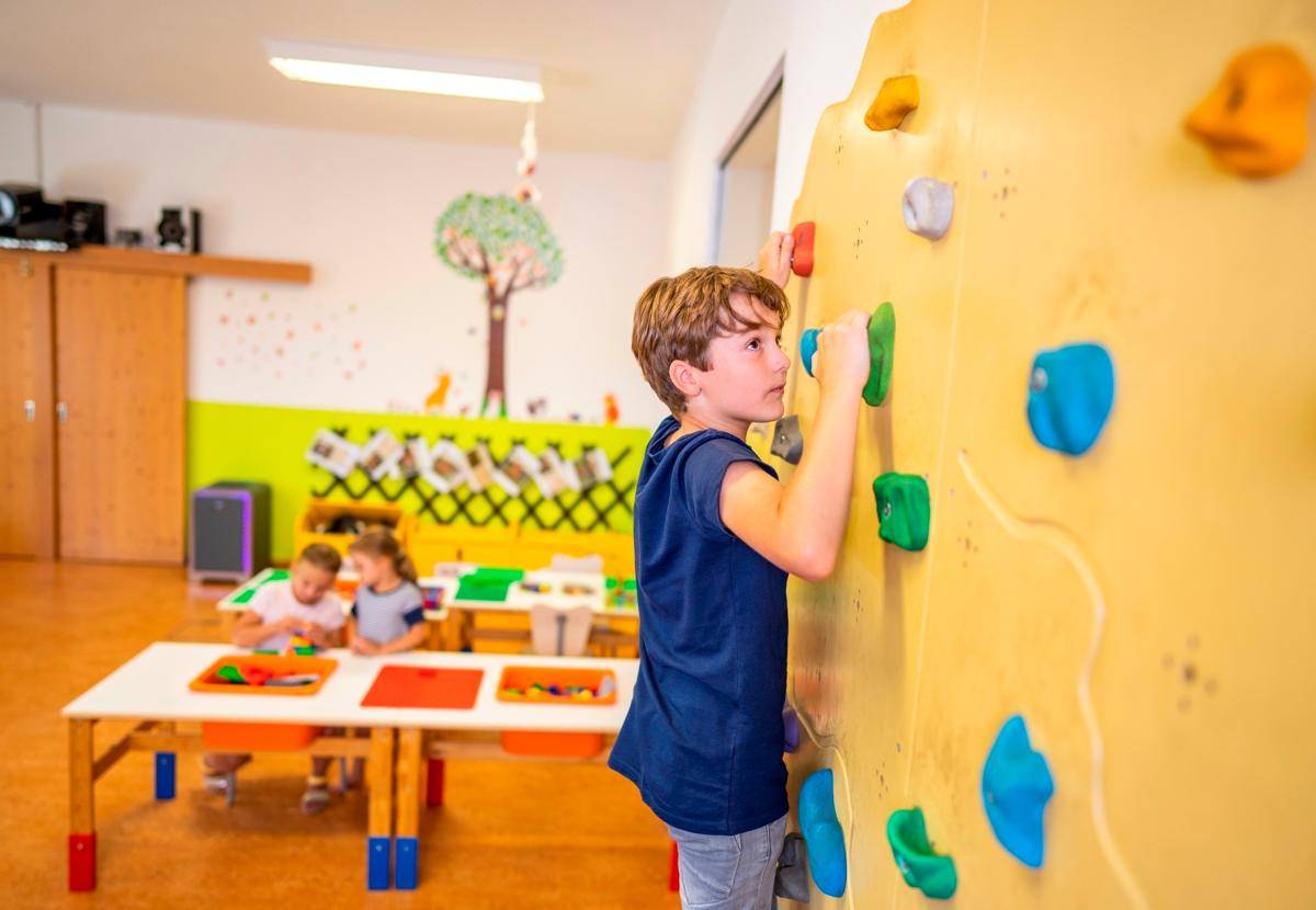 Spielzimmer mit Kletterwand für Kinder und Tischen zum Basteln und Spielen.