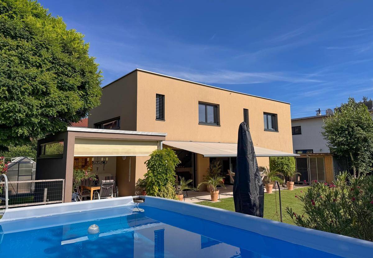 Garten mit Rasenfläche, Terrasse und einem aufgestellten Swimmingpool.