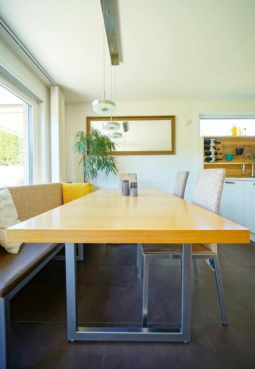 Essbereich in der Küche mit Holztisch, Sitzbank und modernem Hängelampen-Design.