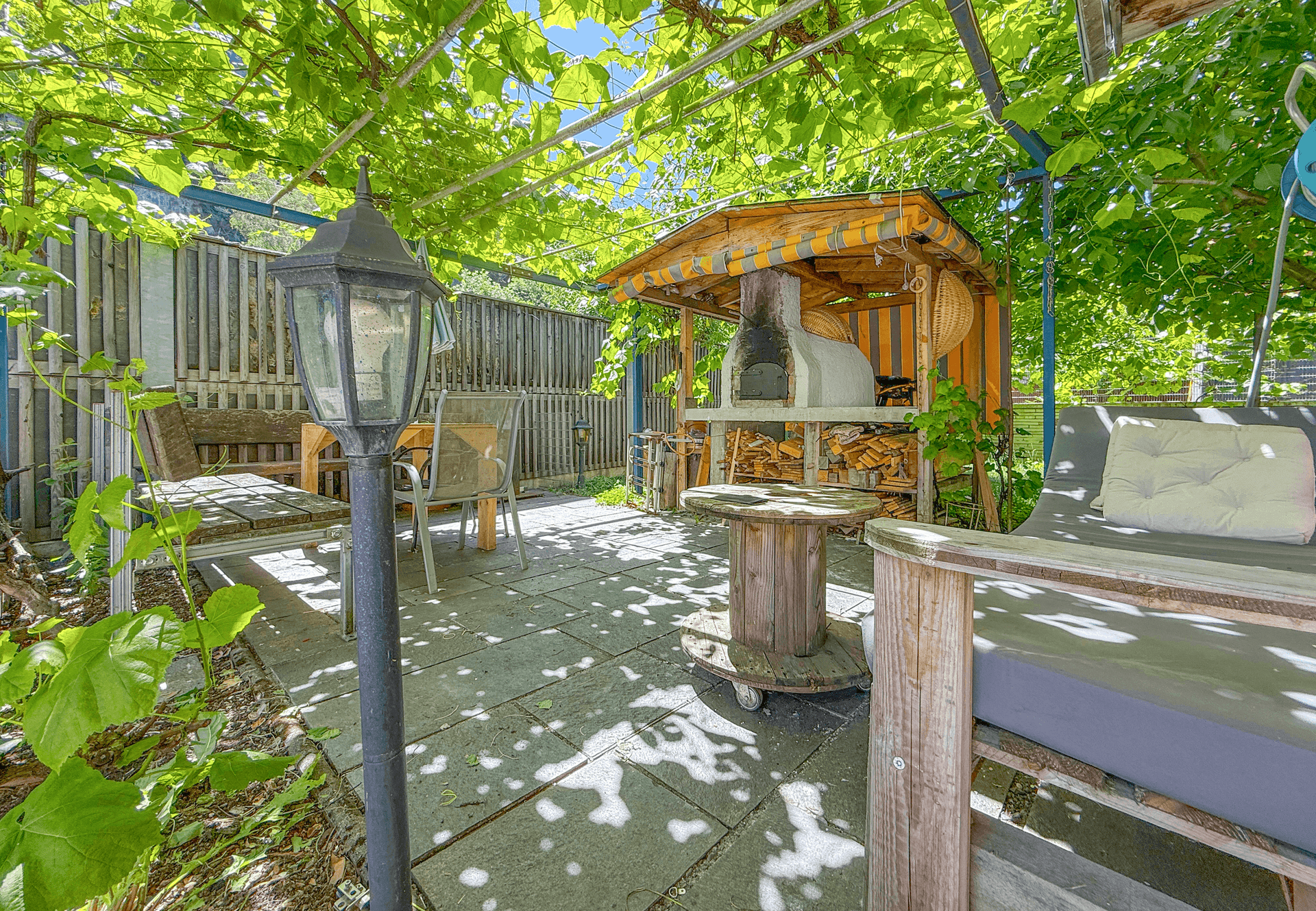 Gemütlicher Gartenbereich mit überdachter Pergola, Sitzgelegenheiten und Pizzaofen, perfekt für Feste.