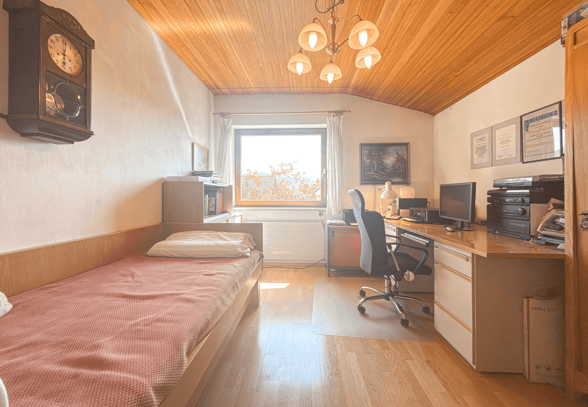 Arbeitszimmer mit Holzdecke, Holzboden und Fenster mit Blick ins Grüne.