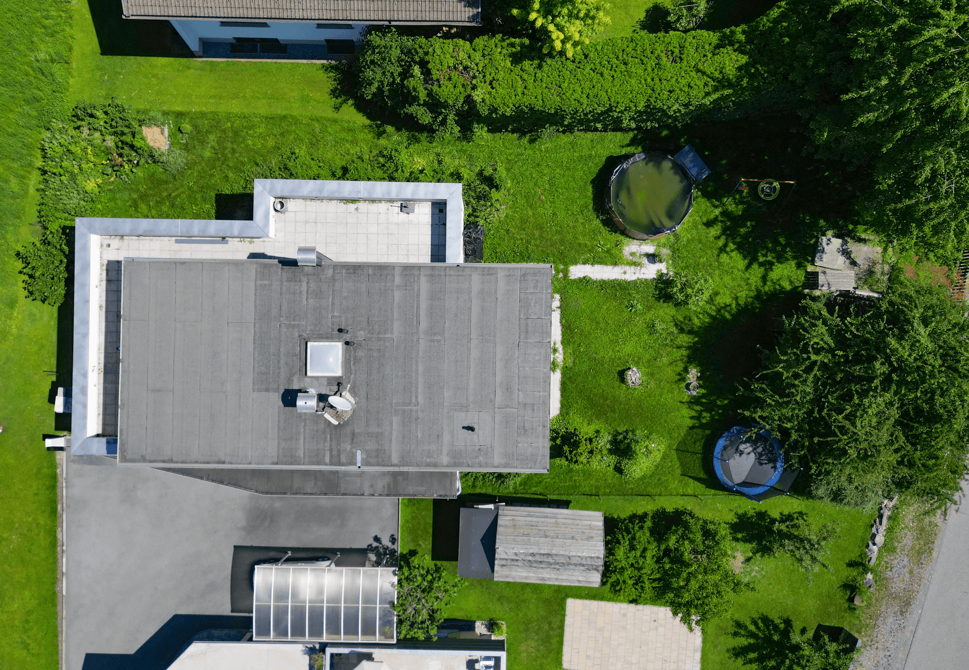 Draufsicht auf das moderne Haus mit Flachdach, Garten und Poolbereich.