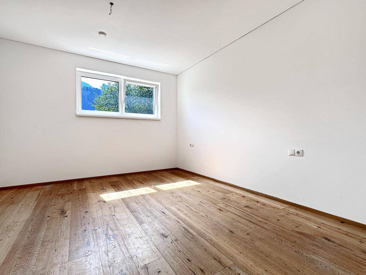 Helles Schlafzimmer mit Holzboden, weißen Wänden und großem Fenster.