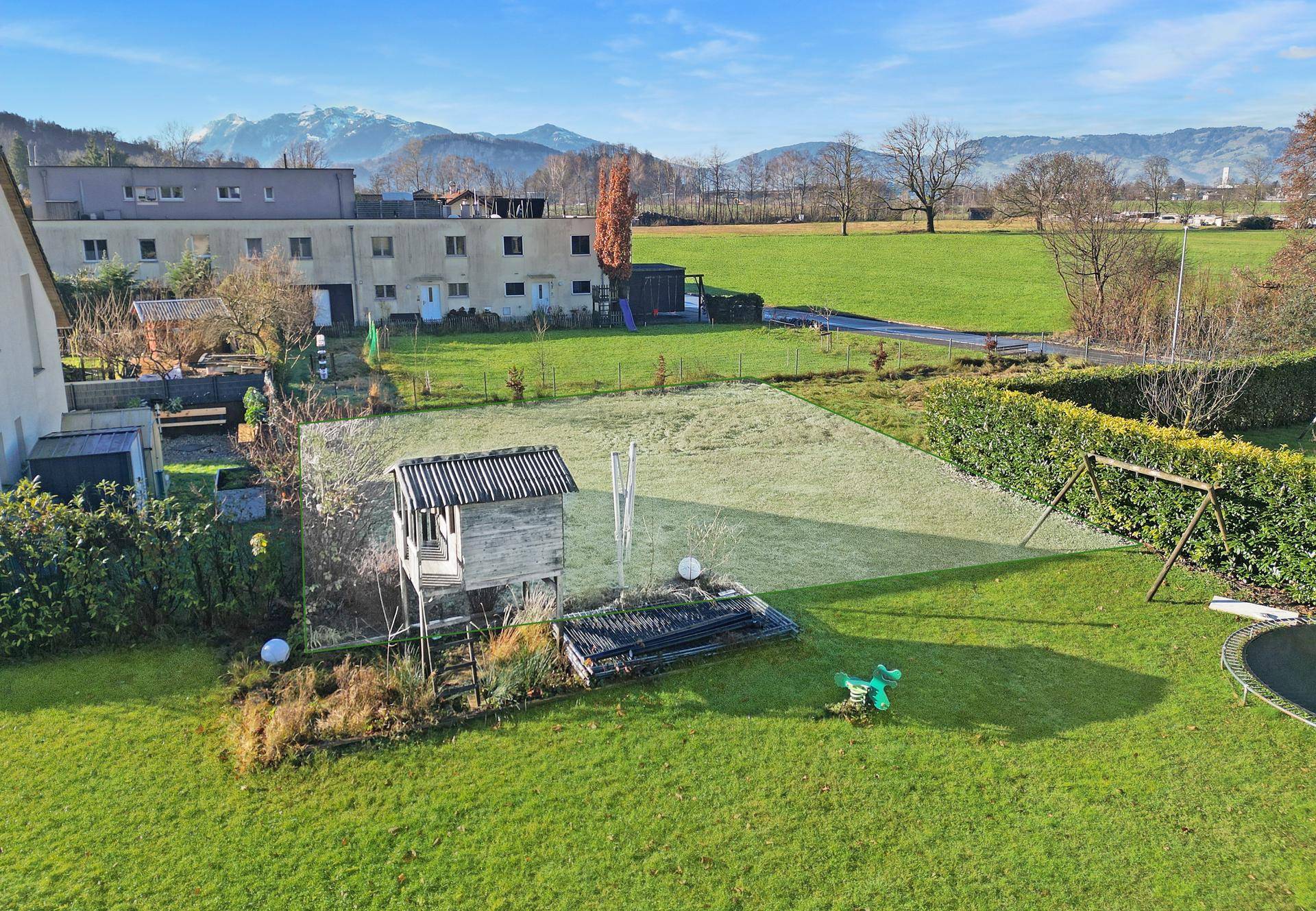 Blick von oben auf ein Grundstück mit Spielgeräten und angrenzenden Feldern.