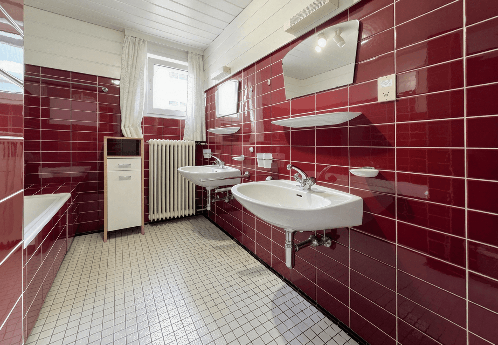 Badezimmer mit roten Fliesen, Doppelwaschbecken, Badewanne und Fenster für Tageslicht.