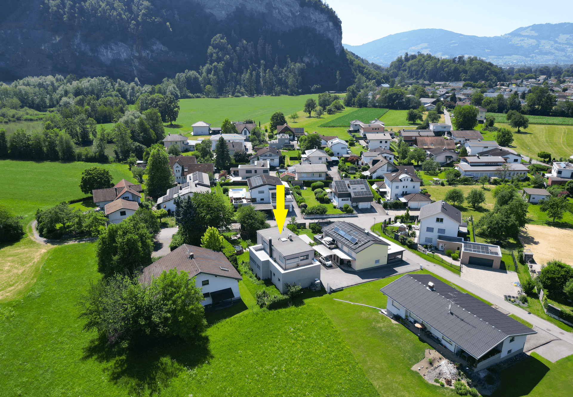 Luftaufnahme des Hauses in ländlicher Umgebung mit Bergen im Hintergrund.