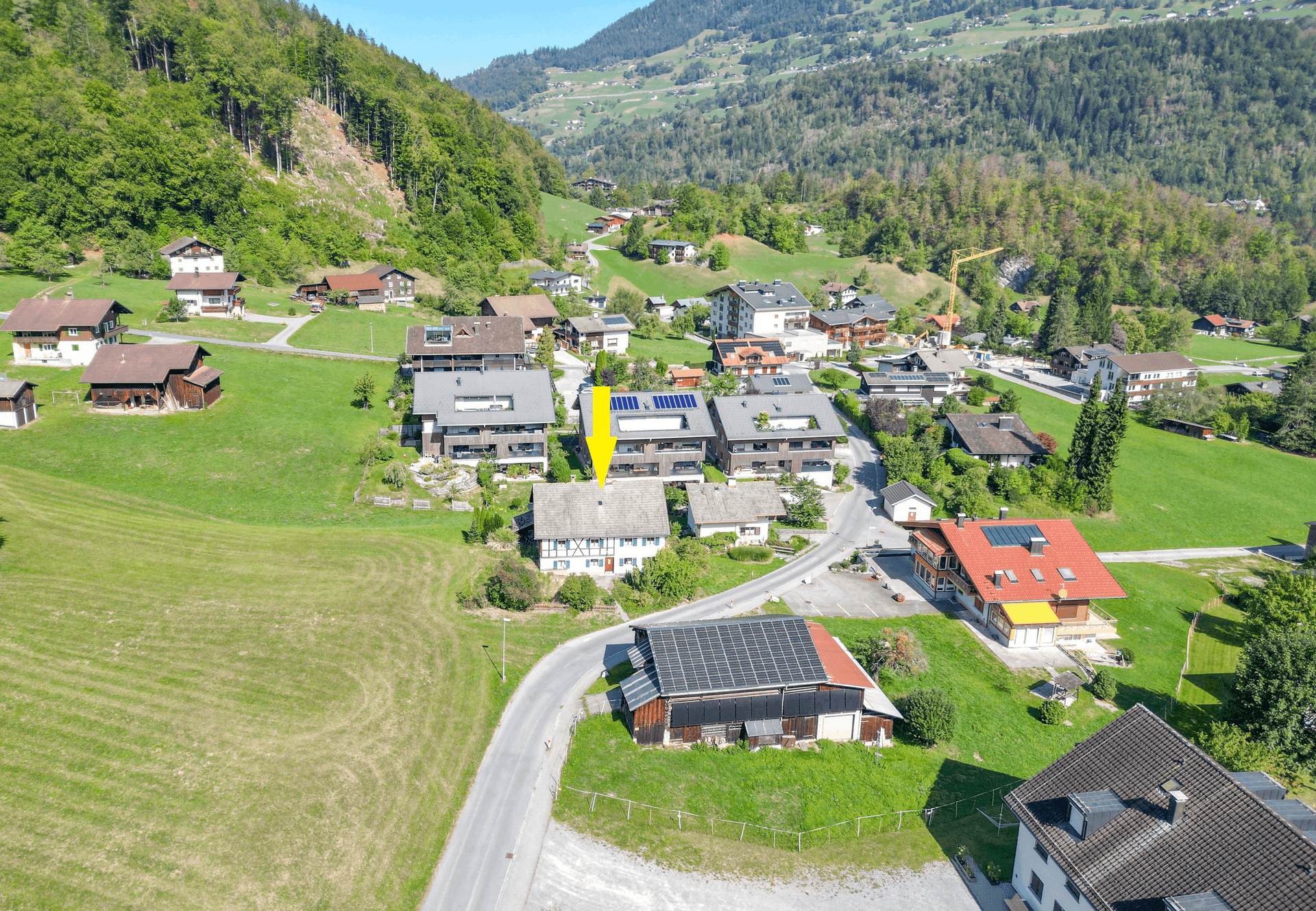 Luftaufnahme des Dorfes mit dem markierten Objekt, eingebettet in eine grüne Berglandschaft.