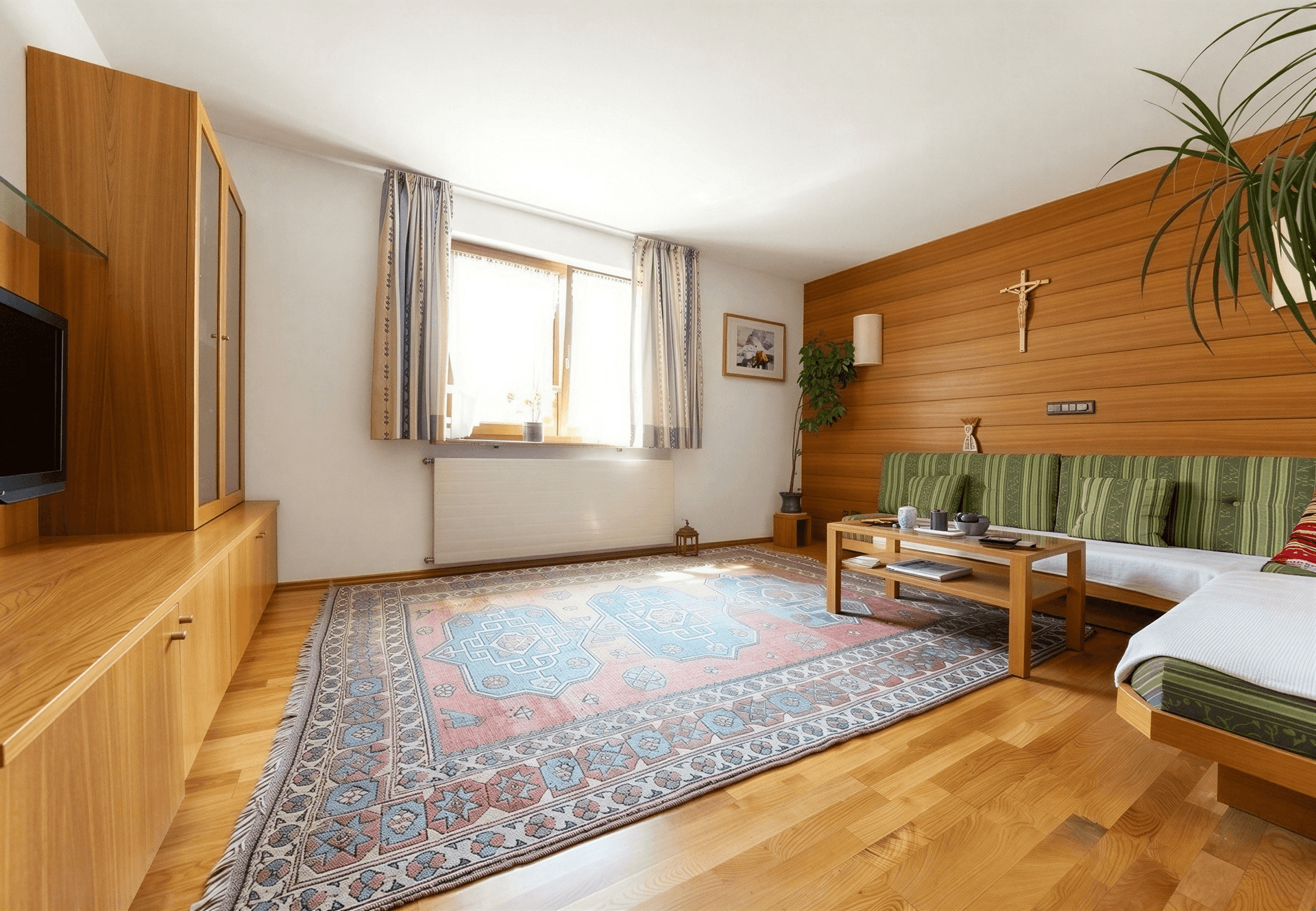 Gemütliches Wohnzimmer im alpinen Stil mit Holzwand, Sofa und Teppichboden.
