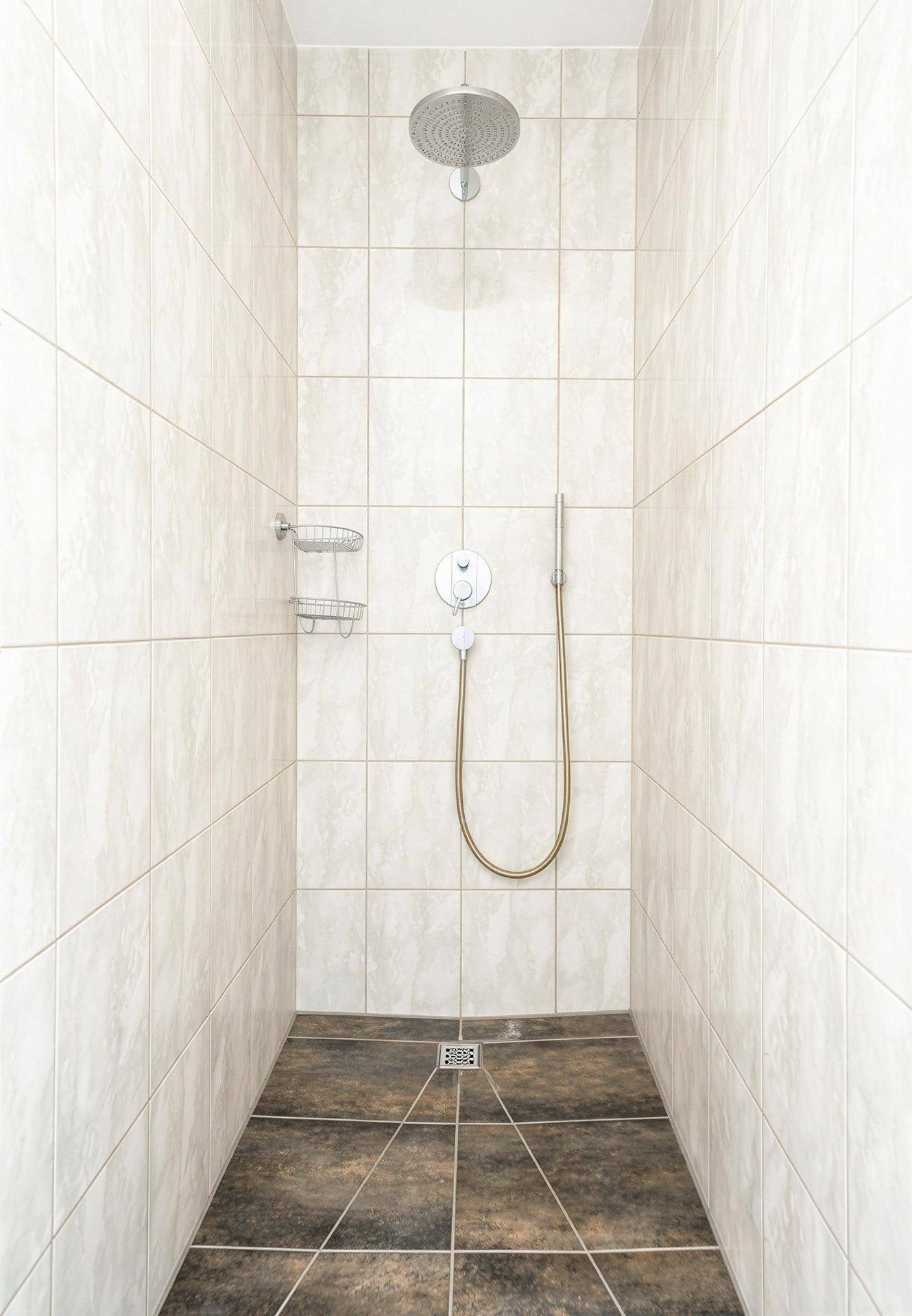 Moderne begehbare Dusche mit Regenduschkopf und hellen Fliesen.