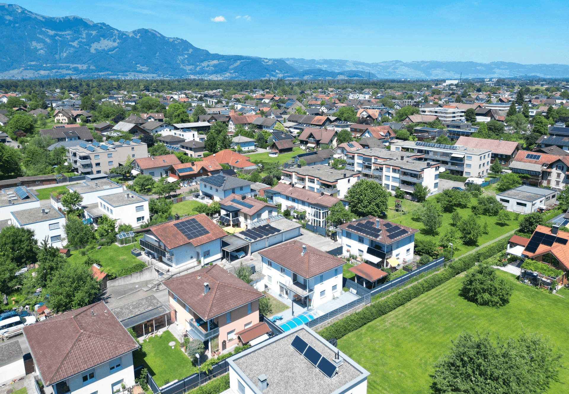 Weitläufige Luftaufnahme einer Wohngegend mit vielen Häusern und grünen Flächen.