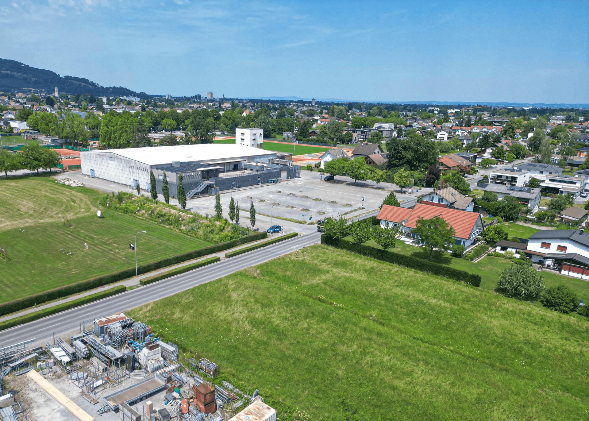 Luftbild der Umgebung mit Sportanlagen, Wohngebäuden und dem unbebauten Grundstück im Vordergrund.