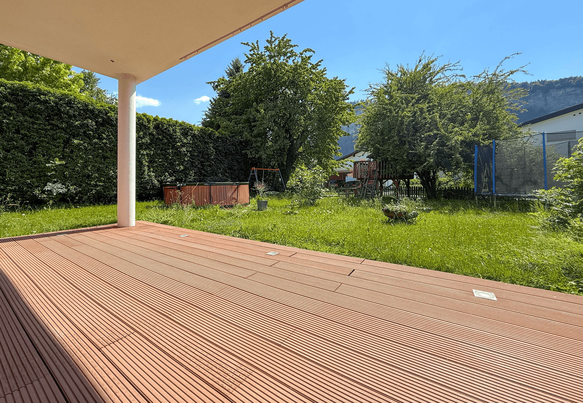 Geräumige Holzterrasse mit Blick auf den grünen Garten und die umliegende Natur.