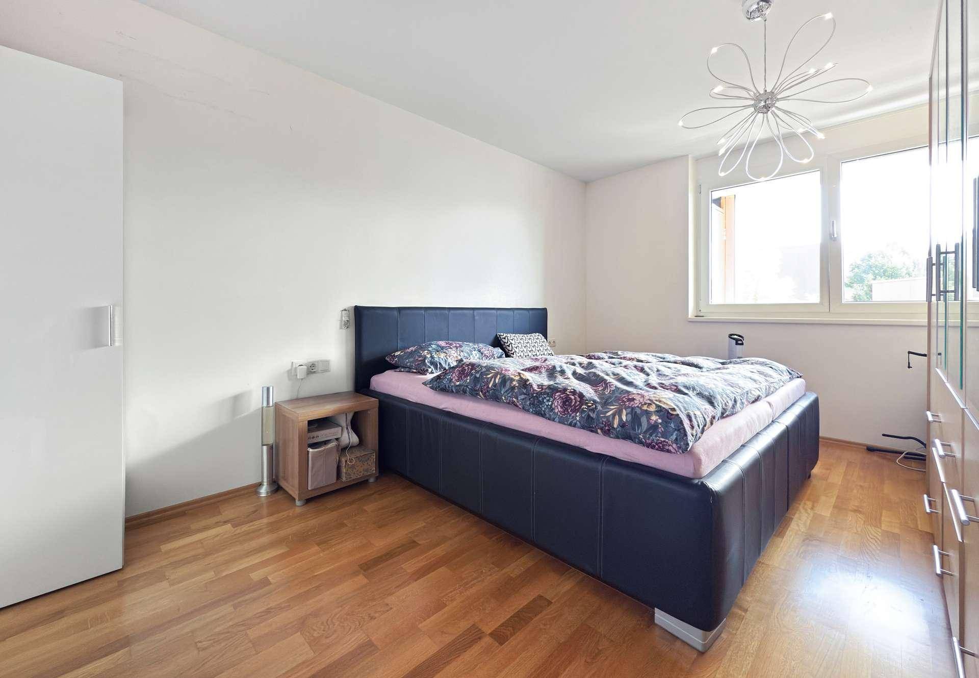 Schlafzimmer mit Doppelbett, Holzboden und großem Fenster für viel Licht.