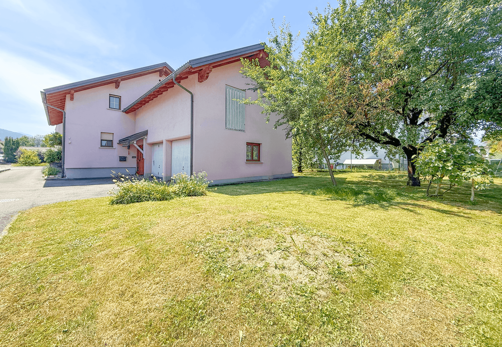 Seitenansicht des Hauses mit großem Garten und Zugang zur Garage.
