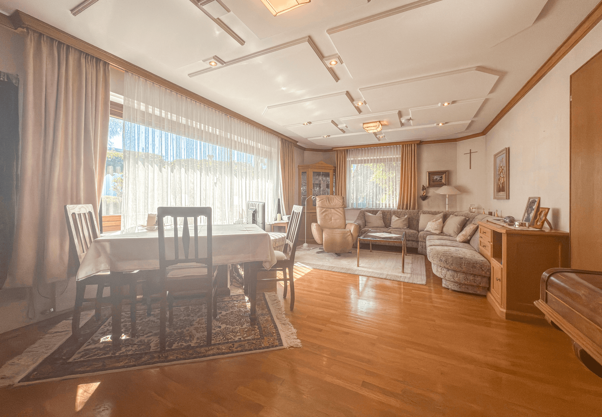Helles Wohn- und Esszimmer mit Parkettboden, großen Fenstern und traditioneller Einrichtung.